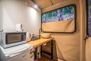 eine Küche in einem Wohnwagen mit einem Tisch und einer Mikrowelle in der Unterkunft Magnetic Glamping Tent 4 in Nelly Bay