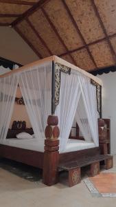 uma cama de madeira com cortinas num quarto em Jungle Inn Bukit lawang em Bukit Lawang