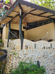 a bed in front of a building with a stone wall at Jungle Inn Bukit lawang in Bukit Lawang