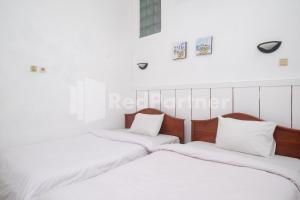 two beds in a room with white walls at Hotel Limaran 1 Syariah Malioboro Mitra RedDoorz in Sentool