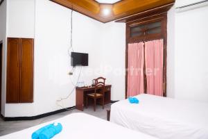 a room with two beds and a desk in it at Hotel Limaran 1 Syariah Malioboro Mitra RedDoorz in Sentool
