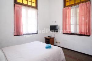 a bedroom with a white bed and two windows at Hotel Limaran 1 Syariah Malioboro Mitra RedDoorz in Sentool