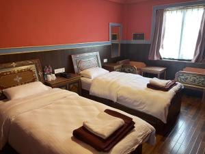 Hotel De Purang في Muktināth: غرفه فندقيه سريرين عليها مناشف