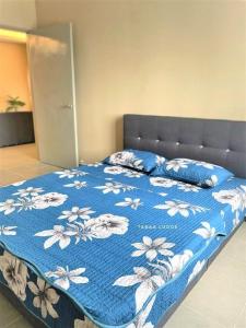 ein Bett mit einer blauen Decke mit Blumen drauf in der Unterkunft Taraa Lodge PutrajayaMuslim in Putrajaya