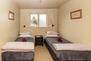 two twin beds in a room with a window at Kaniere Hotel in Hokitika