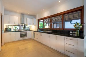 a kitchen with white cabinets and a large window at Jasmina Estate by Villas Direct Bali in Seminyak