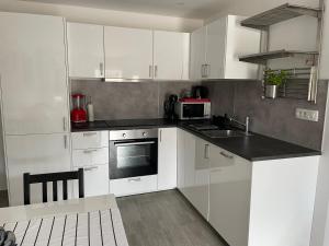 kuchnia z białymi szafkami, zlewem i kuchenką mikrofalową w obiekcie Apartments Tom w Mimicach