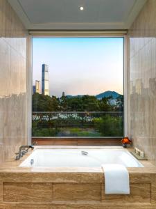 uma banheira na casa de banho com uma grande janela em The Olympian Hong Kong em Hong Kong