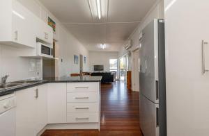 a kitchen with white cabinets and a stainless steel refrigerator at The Cottage 16 Clarke Street Bargara in Bargara