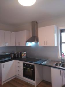 a kitchen with white cabinets and a black counter top at Two separate rooms in Clayton South in Clayton North