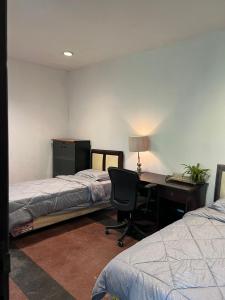 a bedroom with two beds and a desk with a computer at SOETJIPTO HOME STAY VILLA in Jakarta