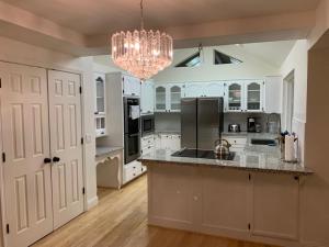 a large kitchen with white cabinets and a chandelier at Executive home in a serene park like setting in Folsom