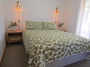 a bedroom with a bed with a green comforter and two lamps at Quandong Beach Shack in Port Moorowie