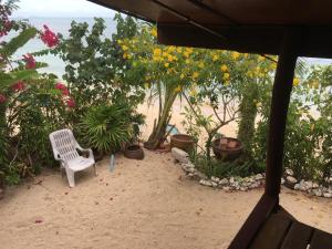 a white chair sitting on the beach with flowers at Bangpo Village Tiny Country Beach House in Koh Samui 