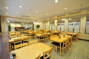 un restaurant vide avec des tables et des chaises en bois dans l'établissement Hiroshima Ekimae Universal Hotel, à Hiroshima