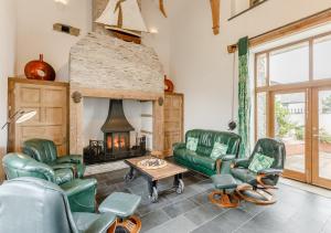 West Down的住宿－Otter Pool Barn，客厅设有绿色椅子和壁炉