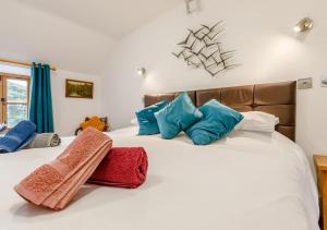 a bedroom with a white bed with blue and red pillows at Otter Pool Barn in West Down