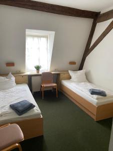 two beds in a room with a window and a chair at Nringrooms Hostel Adenau in Adenau