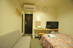 Cette chambre comprend un lit et un bureau avec une télévision. dans l'établissement Hiroshima Ekimae Universal Hotel, à Hiroshima