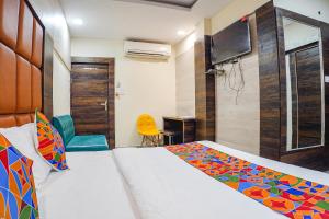 FabHotel Brij Residency في Naiāpura: غرفة نوم بسرير ومكتب وتلفزيون