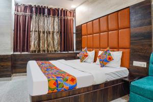 FabHotel Brij Residency في Naiāpura: غرفة نوم بسرير كبير وكرسي ازرق