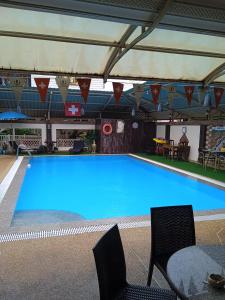 een groot blauw zwembad met 2 stoelen en een tafel bij Udon Thai House Resort & Hotel in Udon Thani