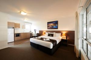 a hotel room with a bed and a kitchen at Takalvan Motel in Bundaberg
