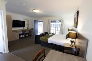 Habitación de hotel con cama y sala de estar. en Takalvan Motel en Bundaberg