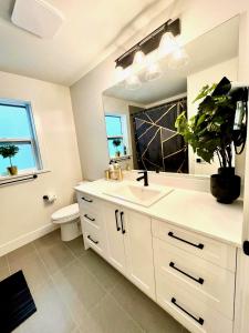 La salle de bains est pourvue d'un lavabo blanc et d'un miroir. dans l'établissement Stylish, Glamorous & Serene 6BR Villa, Near Vancouver, Oasis for Groups and Large Families, à Langley
