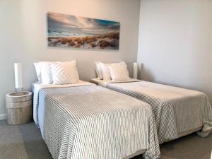 2 letti posti uno accanto all'altro in una stanza di Luxury beachfront apartment a Moana