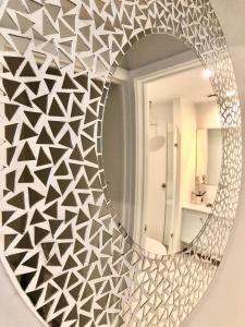 een spiegel met een geometrisch patroon op een muur bij Luxury beachfront apartment in Moana