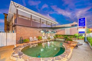 a home with a pool in front of a building at Takalvan Motel in Bundaberg