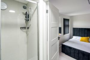 a bathroom with a shower and a bed and a door at CommonSide Luxury in Mitcham