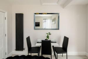 uma sala de jantar com uma mesa, cadeiras e um espelho em CommonSide Luxury em Mitcham