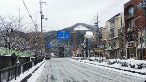 een met sneeuw bedekte straat met gebouwen en een berg bij Thank you so muchya Miyaco in Kyoto