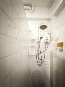 a shower in a bathroom with white tiles at Hobnob Hostel in Chiang Mai