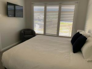 a bedroom with a large white bed and a chair at 21 On Court in Mudgee