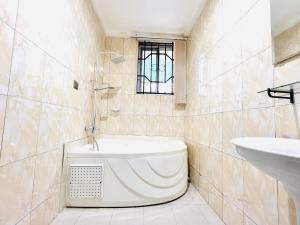 a bathroom with a bath tub and a sink at Aduk Guest House Airport City Accra in Otele