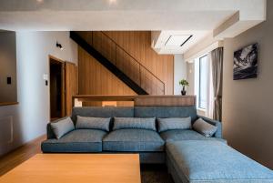 ein Wohnzimmer mit einem blauen Sofa und einem Holztisch in der Unterkunft Higashikawa Asahidake Onsen Hotel Bear Monte in Higashikawa