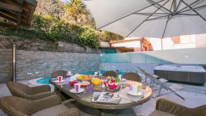 Villa Lucia Laglio في لاليو: طاولة وكراسي مع مظلة على الفناء