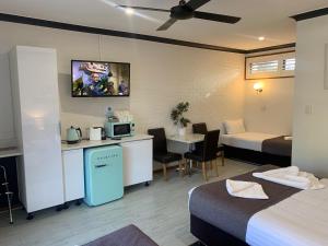 a hotel room with two beds and a kitchen and a table at Kurri Motor Inn in Kurri Kurri