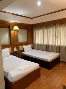 a hotel room with two beds and a window at Imperial Sakon Hotel in Sakon Nakhon