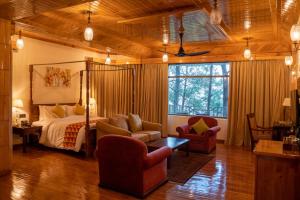 a bedroom with a bed and chairs in a room at Chillaru Spa & Resort in Kasauli