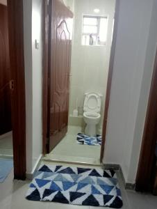 a bathroom with a toilet and a blue rug at Amalya suites by TJ3 in Eldoret