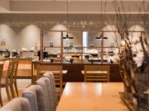 小樽市にあるグリッズプレミアムホテル小樽のテーブルと椅子のあるレストラン、カフェテリア