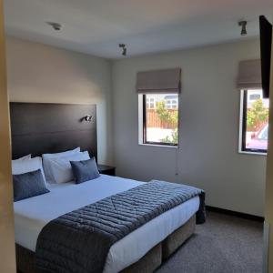 a bedroom with a large bed and two windows at Ava Lodge in Lower Hutt