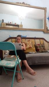 una mujer sentada en una cama usando un portátil en Casa dei fiori en Siracusa