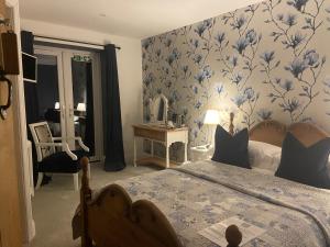 a bedroom with a bed with a blue floral wallpaper at Abbey Green Farm in Wem