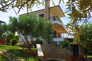 ein Haus mit einem Balkon und Bäumen davor in der Unterkunft Sofia Luxury Maisonettes in Nikiti