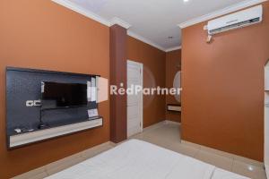 a living room with a tv and a wall at Star Hotel Jaksa Mitra RedDoorz in Jakarta